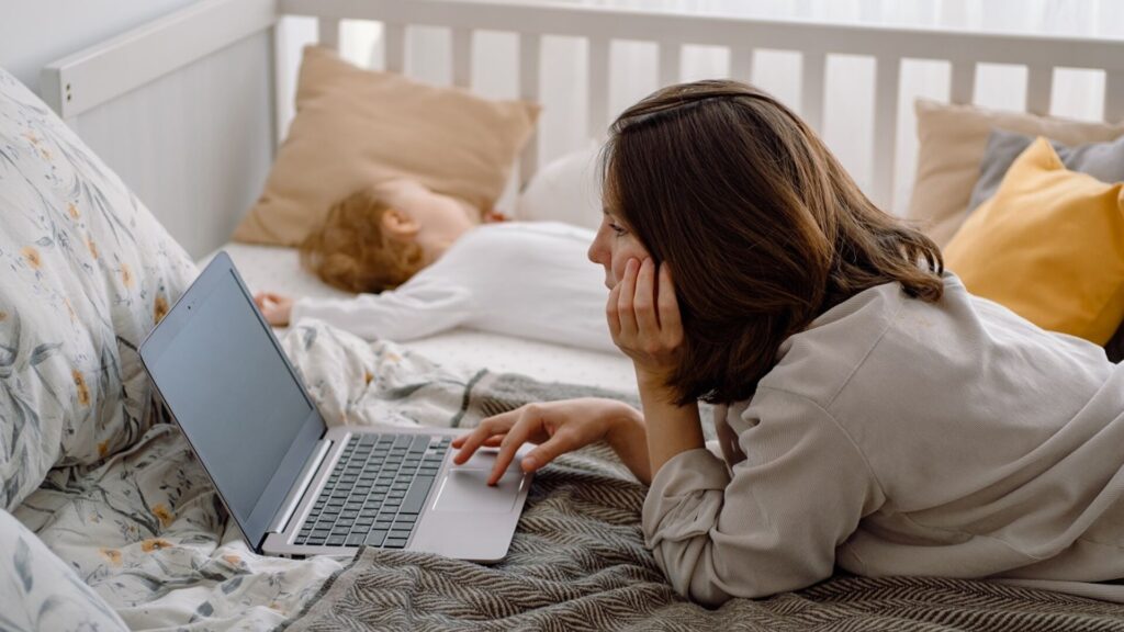 Close,Up,Of,A,Young,Woman,Mother,Using,Laptop,Lying