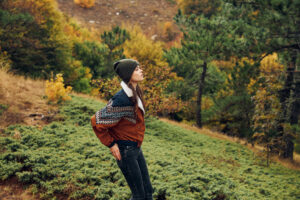 A Peaceful Moment of Solitude Young Woman Standing in Autumn Forest on Grassy Hill surrounded by Nature’s Beauty